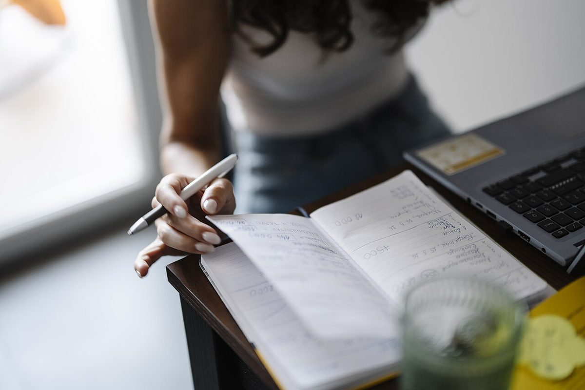 A person writing a list of name ideas in a notebook at a desk