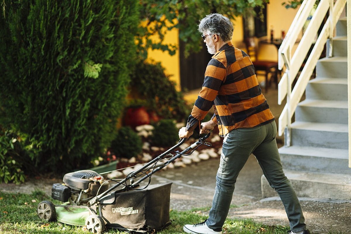A man mowing a lawn in a suburban garden
