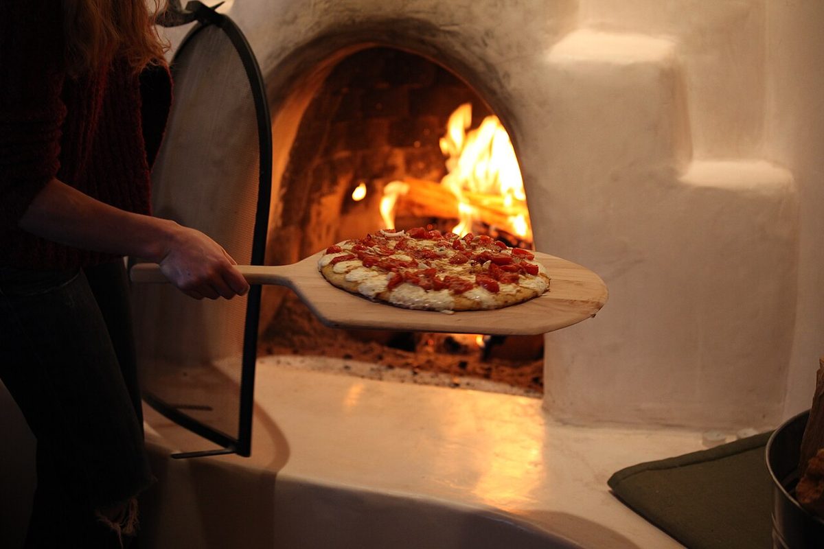A pizza baking in a wood-fired oven